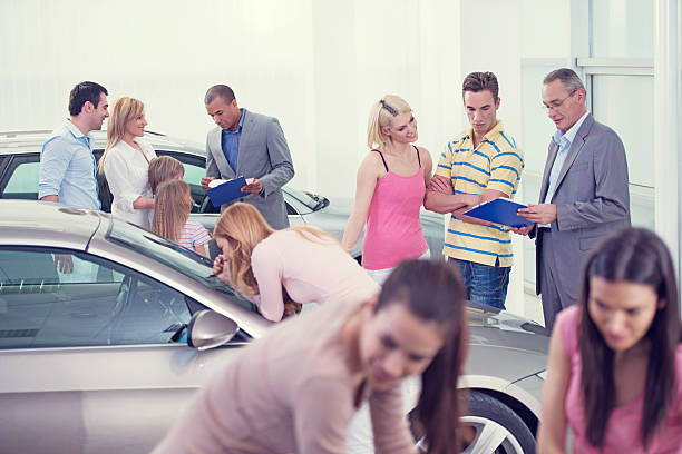Large group of people choosing and buying a new car in showroom.
