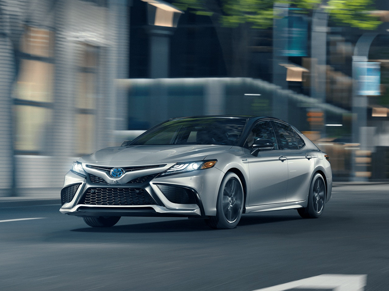 grey 2021 toyota camry hybrid driving on road at night