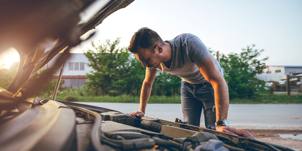 A young man experiencing a mechanical problem with his vehicle out on the road