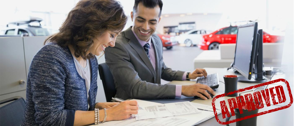 Auto loan approval process showing borrower signing financing documents with dealership finance representative.