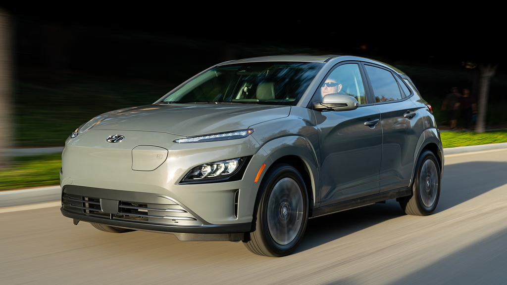 Gray 2022 Hyundai Kona Electric in motion on a sunny urban roadway.