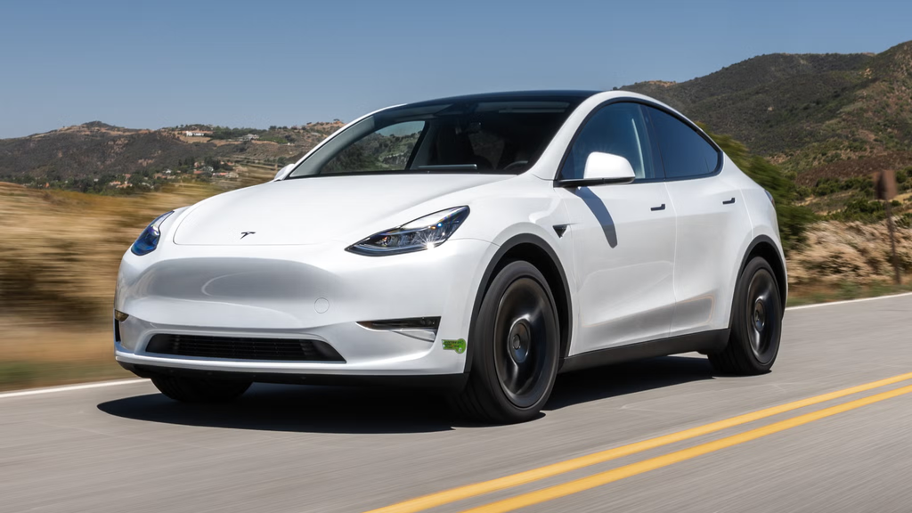 White 2023 Tesla Model Y electric SUV driving on a mountain road in California.