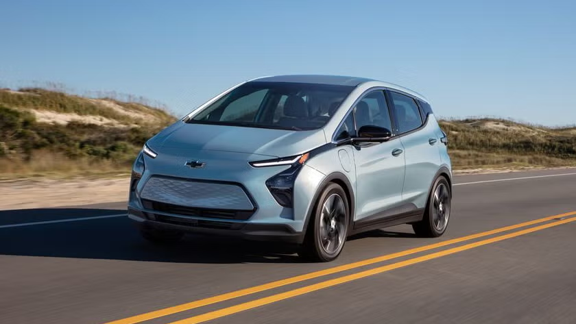 Blue 2023 Chevrolet Bolt EV cruising along a sunny California highway.